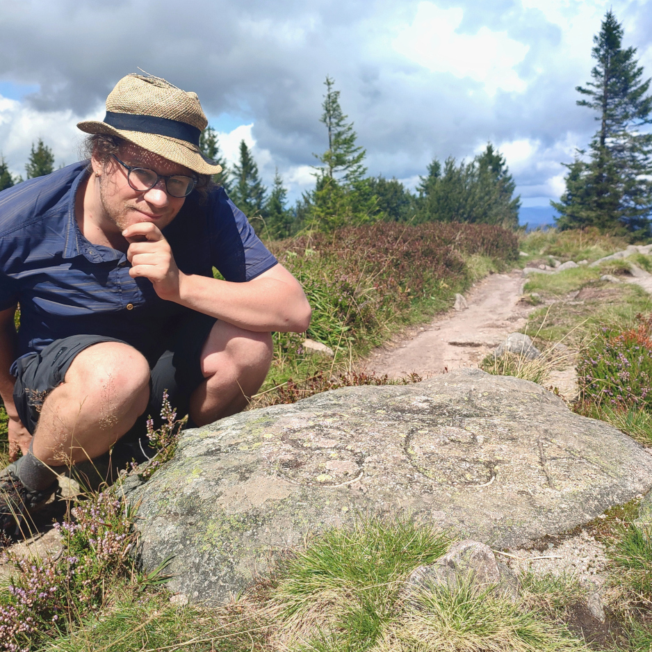 Picture of me in the Vosges mountains in front of a rock with "SGA" carved in